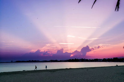 Silhouette people at beach against sky during sunset