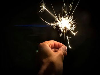 Hand holding firework display at night