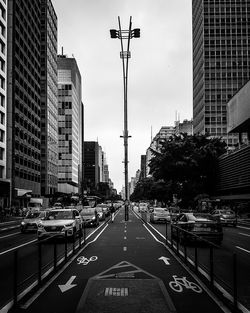 Traffic on road amidst buildings in city against sky