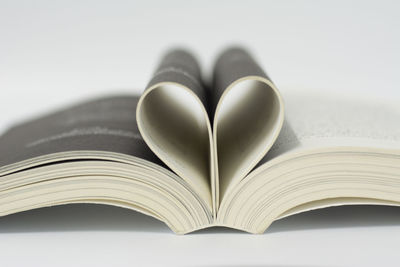 Pages of book in heart shape over white background