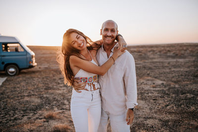 Portrait of young couple standing on land against sky