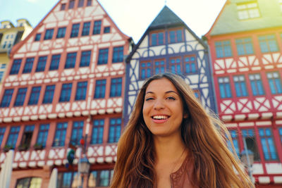 Portrait of smiling young woman against building