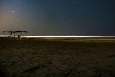 Light trails on beach against sky at night