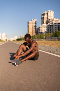 Full length of shirtless man in city against sky