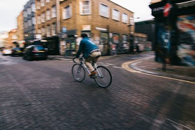 Blurred motion of man riding bicycle on city street