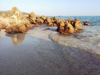 Rocks on beach against clear sky