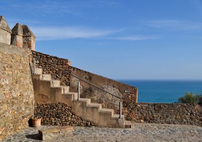 Old building by sea against sky