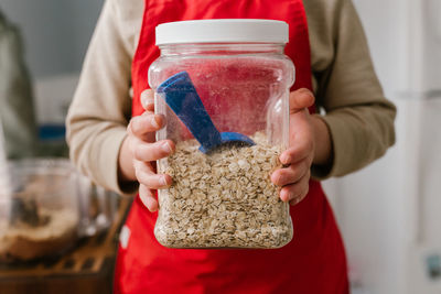 Midsection of woman holding oats jar