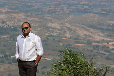 Portrait of mid adult man wearing sunglasses standing on mountain during sunny day