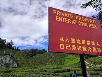 Low angle view of information sign against cloudy sky