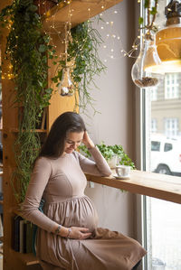 Pregnant woman with hands on stomach sitting in cafe