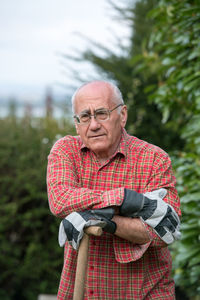 Portrait of senior man standing against trees