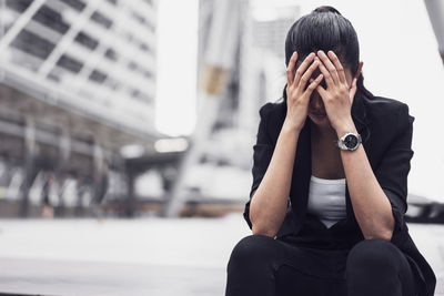 Tensed businesswoman sitting on street in city