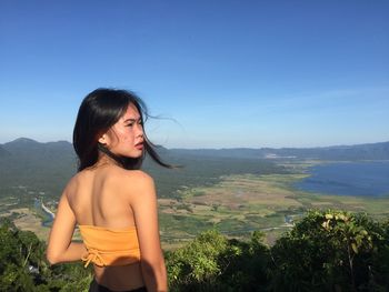 Portrait of young woman standing against sea