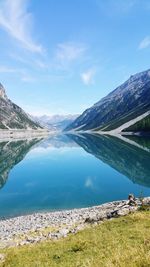 Scenic view of lake and mountains against blue sky