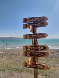 Information sign on beach against sky