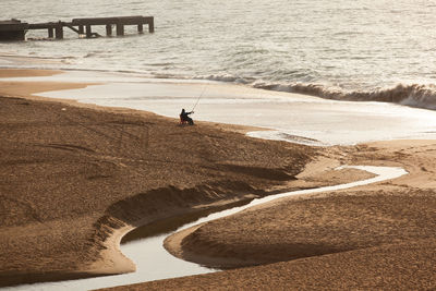 Man fishing on the beach of albufeira early in the morning