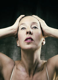 Portrait of young woman against black background