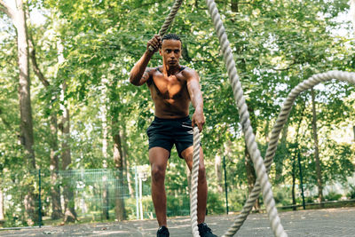 Full length of shirtless man sitting in park