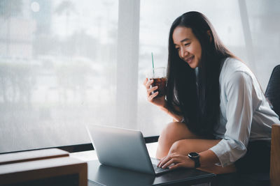 Young woman using mobile phone while sitting on table