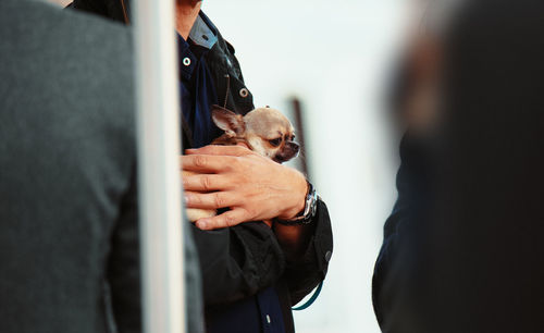 Midsection of man holding dog outdoors