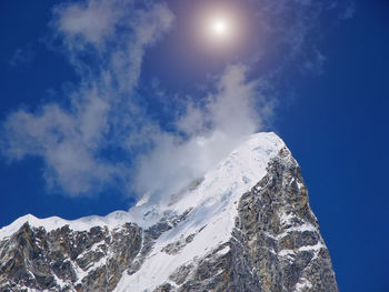 Low angle view of snowcapped mountains against blue sky