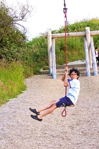 Boy playing on swing at park
