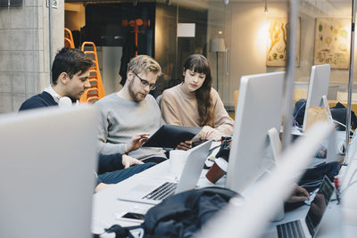 Male and female computer programmers using digital tablet at desk in office