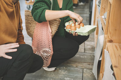 Woman examining eggs in carton by man at shop