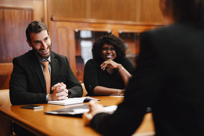 Smiling business colleagues discussing while sitting in conference room during meeting