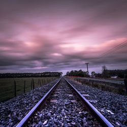 Surface level of railroad track against cloudy sky