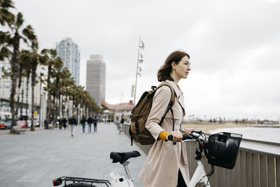 Woman with e-bike having a break on beach promenade