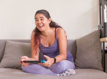 Young woman using phone while sitting on sofa at home