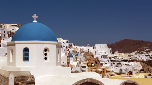 Buildings in city against clear blue sky