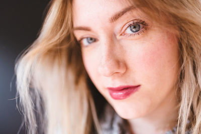 Close-up portrait of young woman against black background