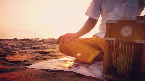 Close-up of man standing on beach at sunset