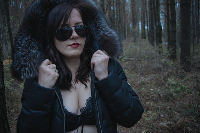 Beautiful woman wearing jacket and sunglasses at forest