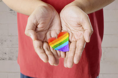 Midsection of man holding heart shape rainbow flag