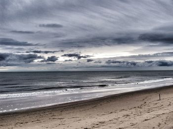 Scenic view of beach against cloudy sky