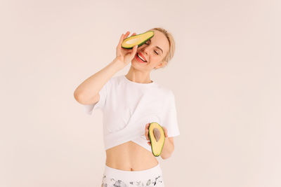 Happy smiling young vegan woman holding green avocado vegetable fruit on white background.copy space