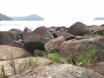 Rocks by sea against clear sky