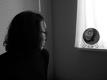 Woman looking into mirror at home