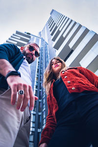 Low angle view of people standing against buildings in city