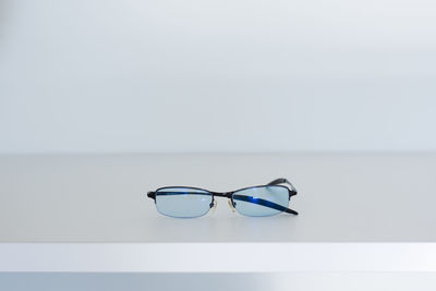 Close-up of eyeglasses on table against white background