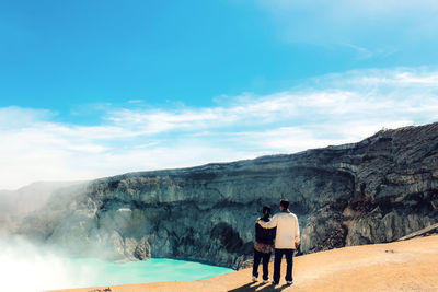 Rear view of friends standing on mountain against sky