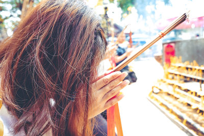 Side view of woman with incense sticks praying outside temple