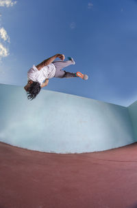 Low angle view of man jumping against sky