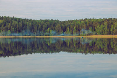 Scenic view of lake by trees against sky