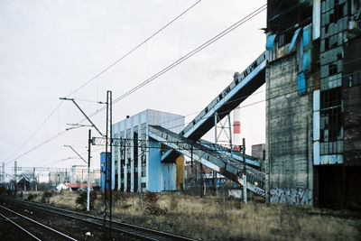 Train on railroad tracks by buildings against sky