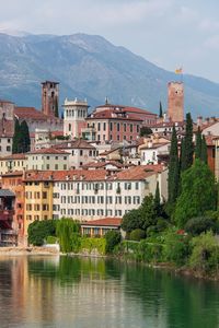 Buildings by lake against sky in town